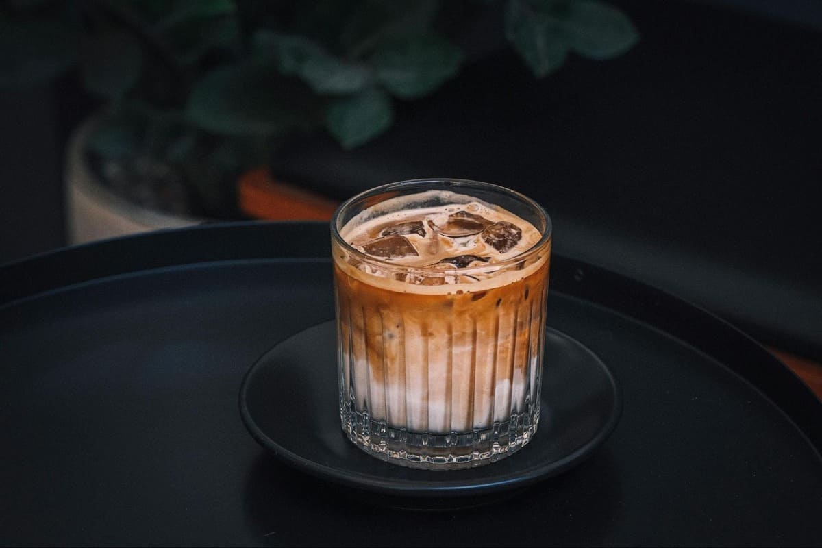 Close-up of a layered iced latte with milk and espresso in a textured glass