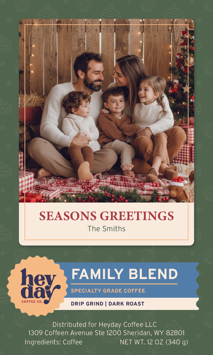 Coffee bag design featuring a holiday-themed label showing a family of four sitting together on a red plaid blanket in front of a wooden wall with string lights and a Christmas tree.