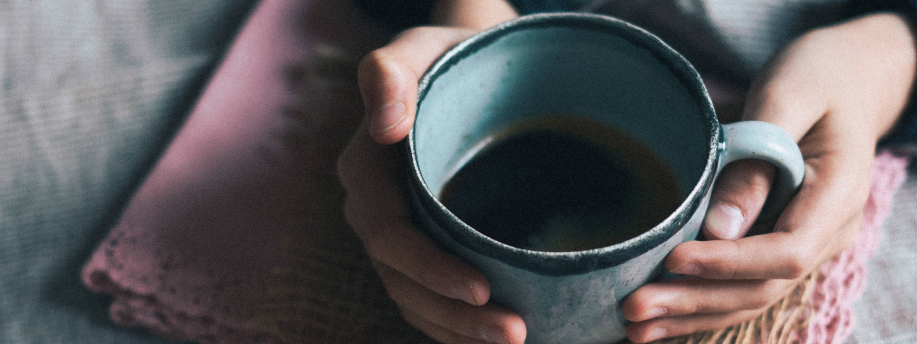 top view of a pair of hands holding a stoneware coffee mug.