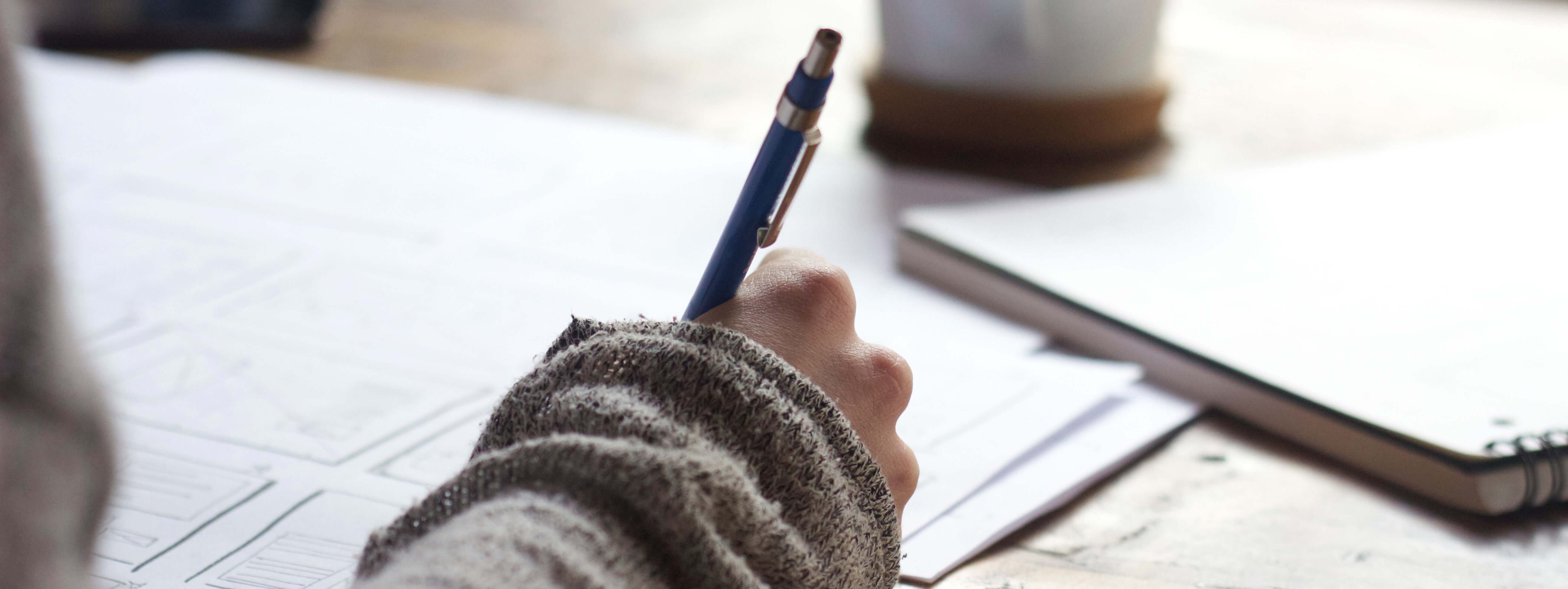 person holding mechanical writing instrument and designing on a large sheet of paper.