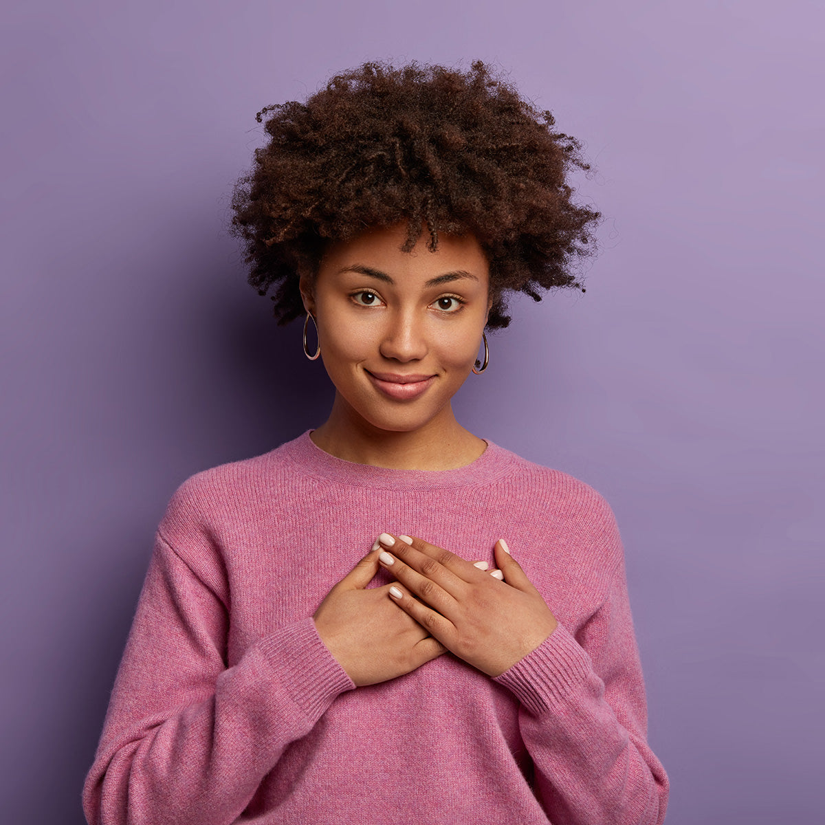 a grateful young woman holding hands to her chest and smiling.